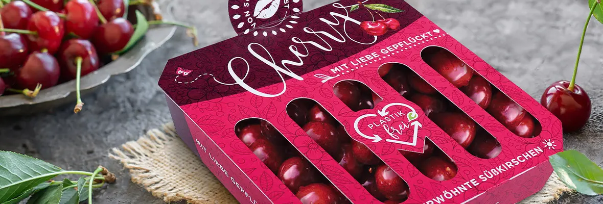 Auf einem Tisch liegt eine markante bunte Verpackung aus Karton für Kirschen.