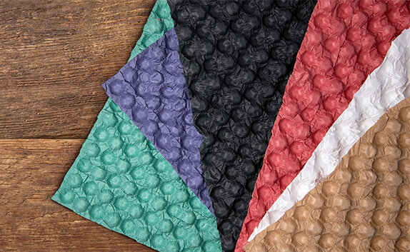 Papierbasiertes Legenest in verschiedenen Farben liegt aufgefächert auf einem Tisch.