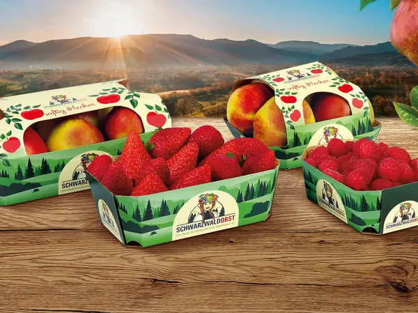 Auf einem Tisch liegen verschiedene Obstverpackungen mit Äpfeln, Erdbeeren und Himbeeren von Schwarzwaldobst