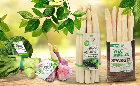 Auf einem Holztisch liegt verschiedenes Gemüse mit bedruckten Etiketten und Banderolen.