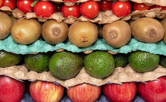 Verschiedene Schichten mit Obst und Gemüse, die mit einem papierbasierten Legenest getrennt sind.